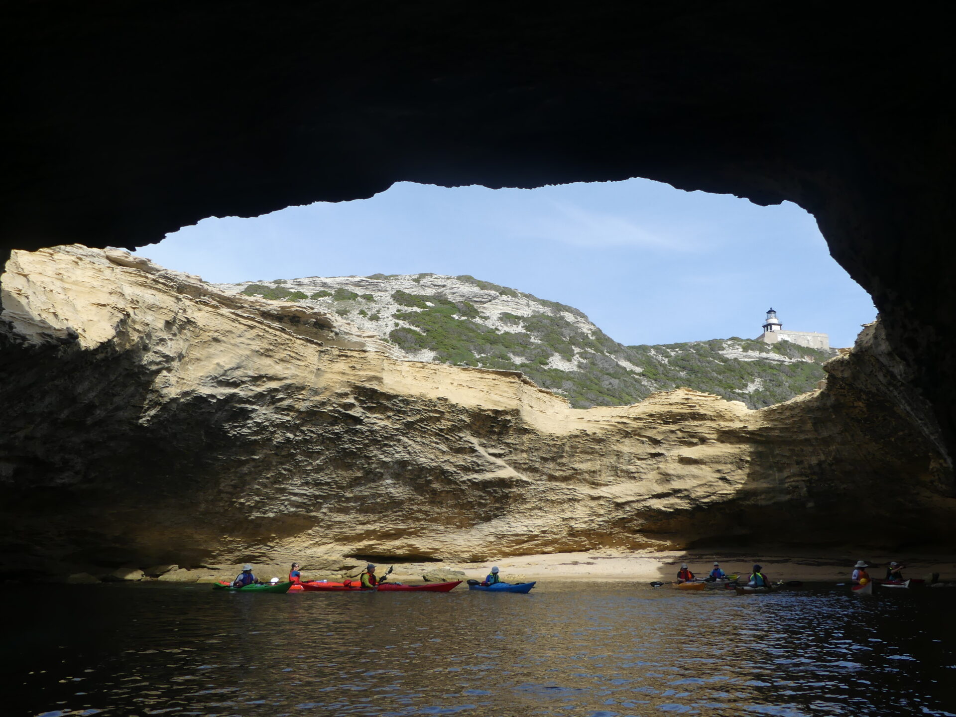 groupe paddling the cave of 'saint antoine' with 'pertusato' lighthouse on the background. groupe de kayakiste dans la grotte de saint antoine avec le phare de pertusato en arriere plan